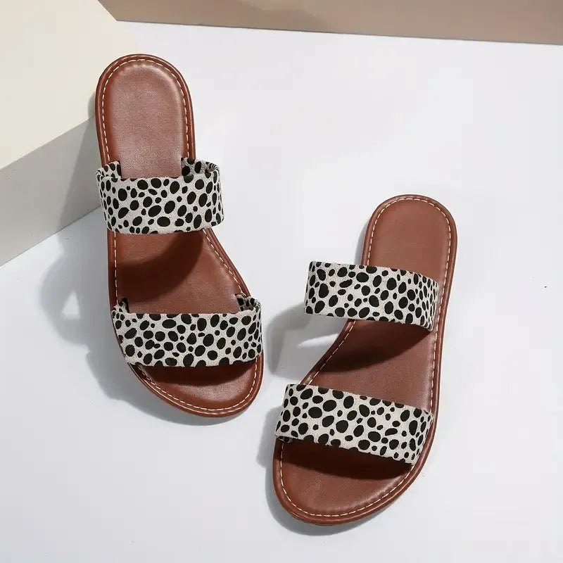 woopify-src:https://manager.labonas.com/wp-content/uploads/2025/07/chaussures-addict-sandales-plate-leopard-tendance.jpg|Paire de sandales plates Léopard de Chaussures Addict avec imprimé léopard, posées sur une surface blanche.